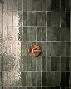 a green tiled shower with a brown handle