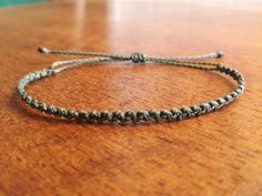 a close up of a string bracelet on a table with a wooden surface in the background