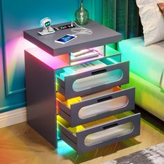 a night stand with three drawers in front of a bed and a phone on the nightstand