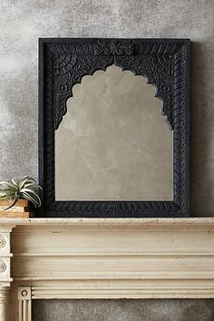 a mirror sitting on top of a mantle next to a potted plant