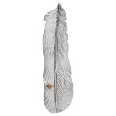 a white feather hanging from the side of a metal hook with a gold button on it