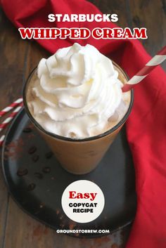 starbucks whipped cream in a cup on a black plate with red and white striped straw