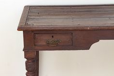 an old wooden table with two drawers on one side and a drawer on the other