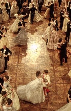 a group of people dressed in formal dress dancing on a floor with other people standing around