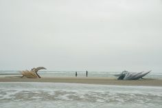 two large boats sitting on top of a sandy beach