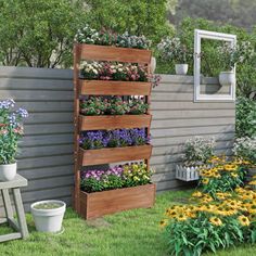 a wooden planter filled with lots of flowers next to a wall covered in potted plants