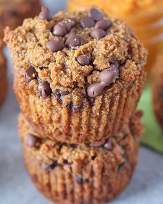 two chocolate chip muffins stacked on top of each other with more muffins in the background