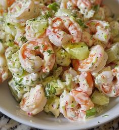 a white bowl filled with shrimp and celery salad on top of a table