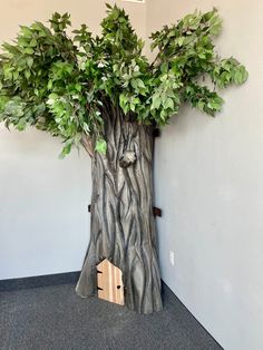 a tree trunk with a birdhouse in it and some green leaves on the top