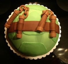 a green cake with chains on it sitting on a table