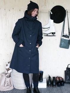 a woman standing in front of a wall with skis and boots hanging on it