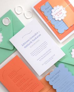 the wedding stationery is laid out on top of different colored envelopes and papers