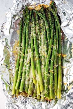 asparagus wrapped in tinfoil on top of aluminum foil, ready to be cooked