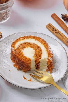 a piece of cake on a plate with a fork and some cinnamon sticks next to it