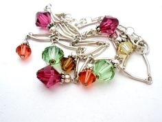 a bunch of different colored beads on a silver chain bracelet with charms attached to it