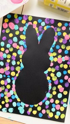 the silhouette of a bunny is painted on a black background with colorful circles and confetti