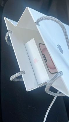 an open white paper bag sitting on top of a black table next to an apple phone