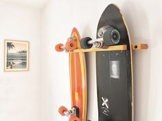 a skateboard mounted to the side of a white wall next to a wooden shelf