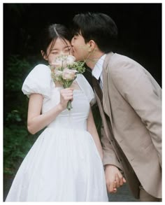 a couple kissing each other while holding flowers