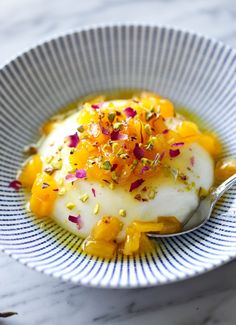 a white bowl filled with food on top of a marble countertop next to a spoon