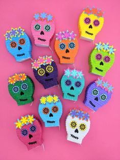 crocheted sugar skulls with flowers on them are arranged in a circle against a pink background