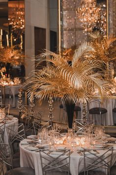 a table set up with silver chairs and palm tree centerpieces