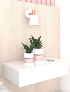 two potted plants sit on top of a white shelf next to a cell phone