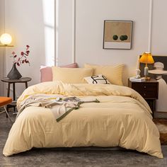 a bed with yellow linens and pillows in a white room next to a chair