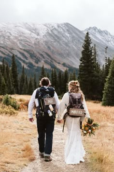 the bride and groom are walking together down the path to their destination in the mountains