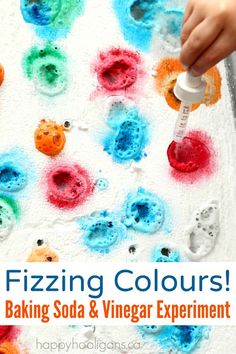 a close up of a child's hand holding a paintbrush over baking soda and vinegar experiment