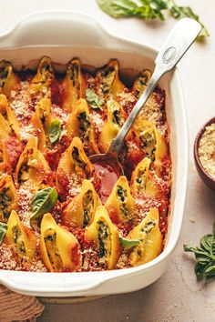 a white casserole dish filled with pasta and spinach