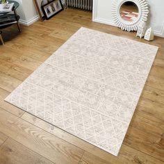 a large white rug in the middle of a room with wood floors and a fireplace