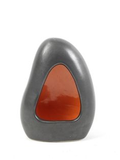 a black and orange vase sitting on top of a white table