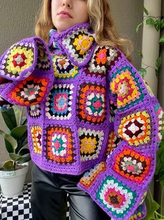 a woman wearing a purple crocheted jacket with colorful granny grannys on it