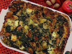 a casserole dish with spinach and potatoes in it on a table next to an apple