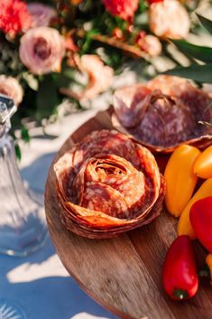 several different types of food are on a wooden platter with flowers in the background