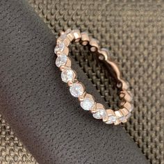 a rose gold ring with white stones on it sitting on a black fabric surface in the sunlight