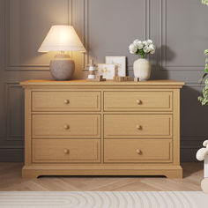 a white teddy bear sitting on top of a dresser next to a vase with flowers