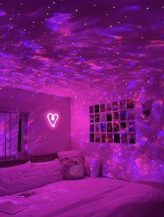 a bed room with a purple glow in the ceiling and pictures on the wall above it