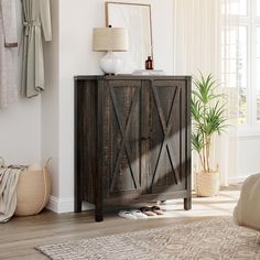 a wooden cabinet sitting on top of a hard wood floor next to a lamp and potted plant