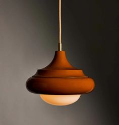 a brown light hanging from a ceiling in a room with dark walls and flooring