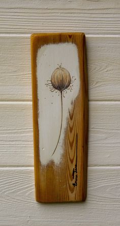 a wooden plaque with a dandelion painted on it