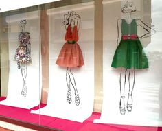 three mannequins with dresses drawn on them in a store front window display