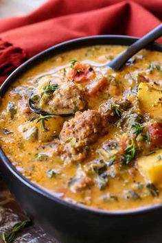 a bowl of soup with meat, potatoes and herbs in it on a wooden table