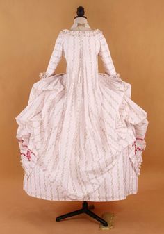 Our Pastel Striped Rococo Gown is a sartorial tribute to the enchanting opulence of the 18th-century court. Drawing inspiration from the sumptuous attire of Marie Antoinette, this dress exudes a baroque style richness with its soft pastel stripes and delicate floral lace trim. The Victorian ball gown silhouette is reimagined for the modern age, crafted to highlight the beauty of plus-size proportions. Lavish rosette adornments and intricate lace details hark back to the grandiose Rococo era, mak Marie Antoinette Gown For Costume Party, Pink Elegant Gown For Costume Party, Elegant Pink Gown For Costume Party, Fitted Floor-length Marie Antoinette Style Dress, Historical Rococo Dress With Baroque Design, Marie Antoinette Style Baroque Dress For Costume Party, Rococo Style Ball Gown With Ruffles, Rococo Ball Gown With Ruffles, Rococo Long Sleeve Costume Dress