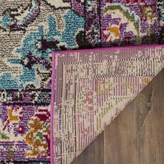 an area rug with various colors and designs on it, laying on top of a wooden floor