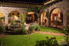 an outdoor courtyard at night with potted plants and greenery on either side of the walkway