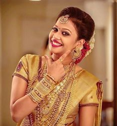 a woman in a yellow sari smiles and poses for the camera with her hand on her chin