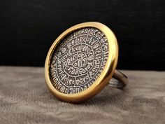 DESCRIPTION - Sterling Silver 925 - Ring - Gold Plated - Ancient Greek Minoan Phaistos Disc - Disc Diameter : 26 mm - 1.01 inches - Brand New - Stamped  925 - Made In Greece ETSY STORE Home Page : http://www.etsy.com/people/silveradosilverjewel?ref=si_pr Shop Page : http://www.etsy.com/shop/SilveradoJewellery?ref=pr_shop_more SHIPPING We ship worldwide using Registered Post Mail and we also provide you tracking number for easy tracking anytime. Shipping carrier : ELTA GREEK POST OFFICE PAYMENT We accept PAYPAL , Credit Cards Thank you very much or Efcharisto poli ( in Greek ) ! Hallmarked Round Bronze Jewelry, Bronze Round Hallmarked Jewelry, Ceremonial Silver Engraved Ring Stamped 14k, Ceremonial Silver Engraved Ring, Stamped 14k, Hallmarked Brass Engraved Ring, Symbolic Etched Jewelry For Commemoration, Unique Etched Round Jewelry, Antique Round Jewelry For Commemoration, Antique Commemorative Round Jewelry