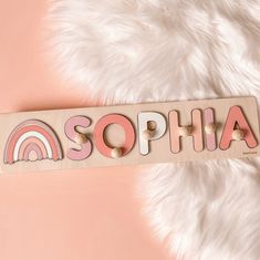 a wooden name puzzle with the word sophia spelled in pink and white letters